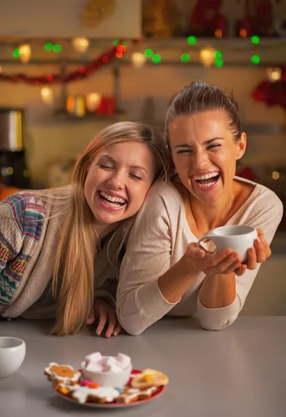 Улыбаясь двум девушкам, которые едят рождественские закуски в рождественском вечере — стоковое фото