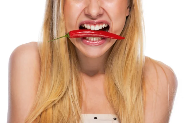 Närbild på tonårsflicka håller röd chili peppar i munnen — Stockfoto