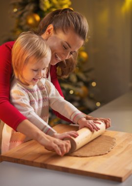 gülümseyen anne ve bebek oklavayla hamuru süslenmiş Noel