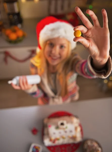 Primer plano en la chica adolescente en sombrero de santa mostrando candie en la cocina decorada de Navidad — Foto de Stock