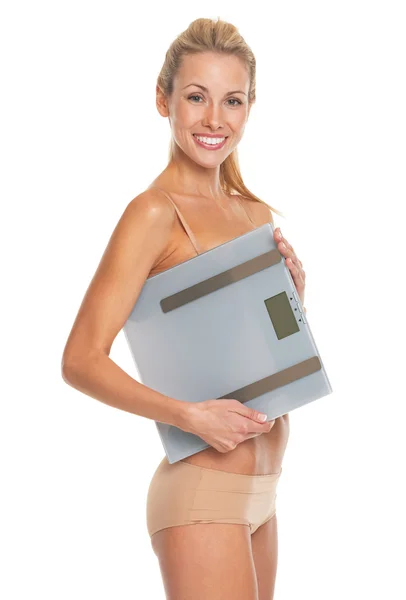 Smiling young woman in lingerie holding scales — Stock Photo, Image