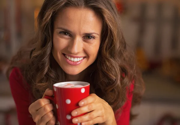 Mujer joven sonriente en vestido rojo de Navidad que tiene una taza de chocolate caliente — Foto de Stock