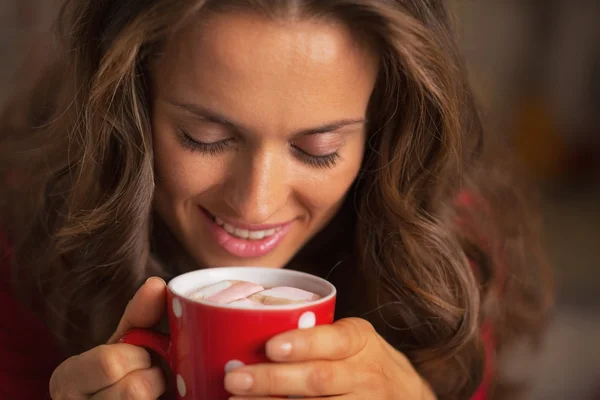 Smiling young woman in red dress having snack in christmas decorated kitchen — Stock Photo, Image