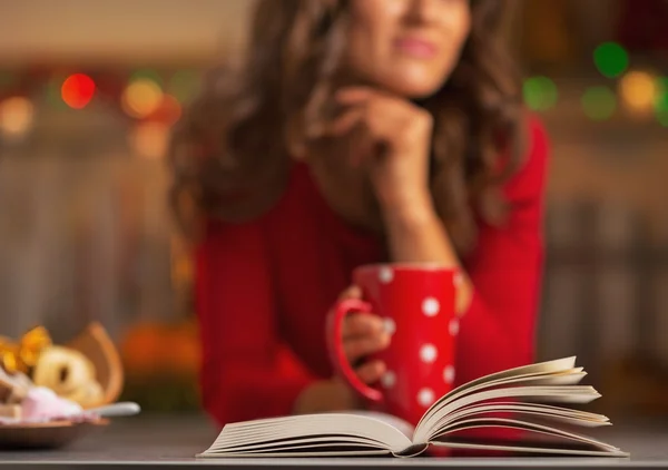 Libro y mujer joven reflexiva con taza de chocolate caliente —  Fotos de Stock