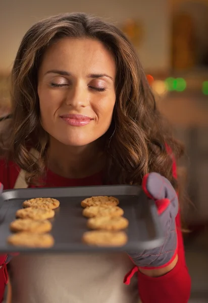Happy young housewife enjoying smell of christmas cookies on pan — Stock Photo, Image