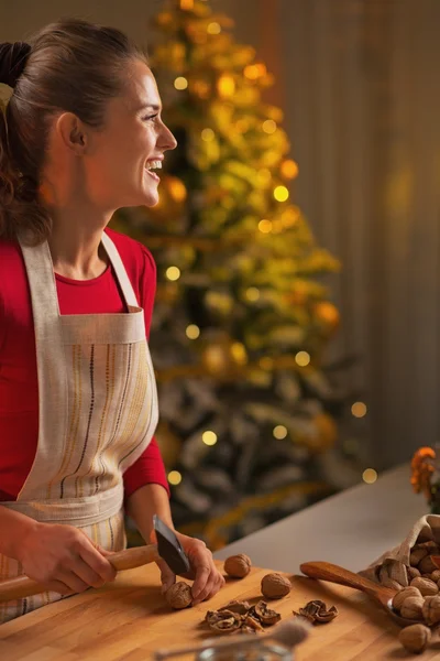 Happy young woman chopping walnuts in christmas decorated kitchen — Stock Photo, Image