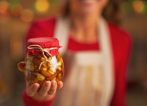 Gros plan sur jeune femme au foyer montrant pot avec des noix de miel — Photo