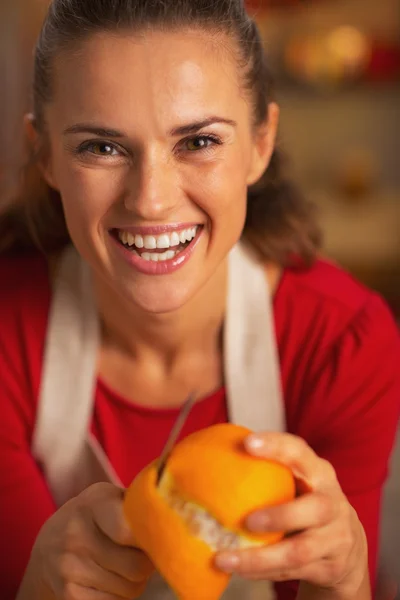 Retrato de feliz jovem dona de casa removendo casca de laranja — Fotografia de Stock