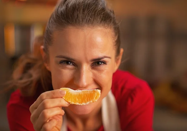 Feliz joven ama de casa sosteniendo naranja en frente de la cara — Foto de Stock