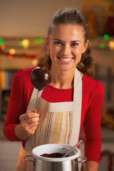 Portrait of happy young housewife showing apple in chocolate glaze — Stock Photo, Image
