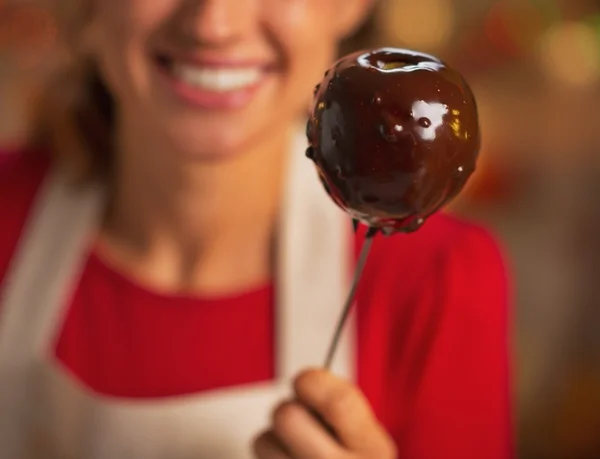 Retrato de ama de casa joven mostrando manzana en esmalte de chocolate — Foto de Stock