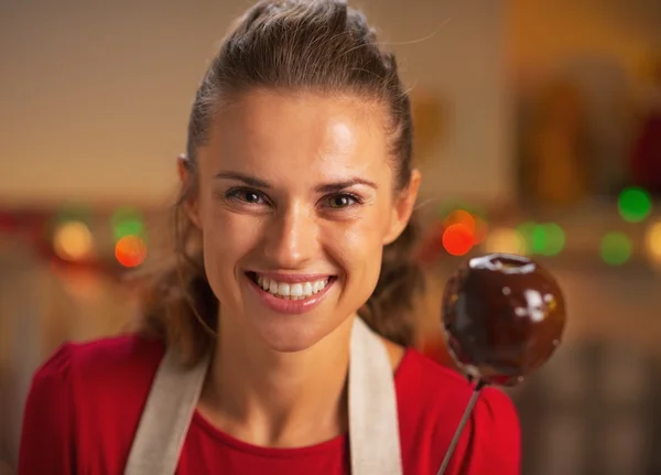 Retrato de la joven ama de casa sonriente mostrando manzana en esmalte de chocolate — Foto de Stock