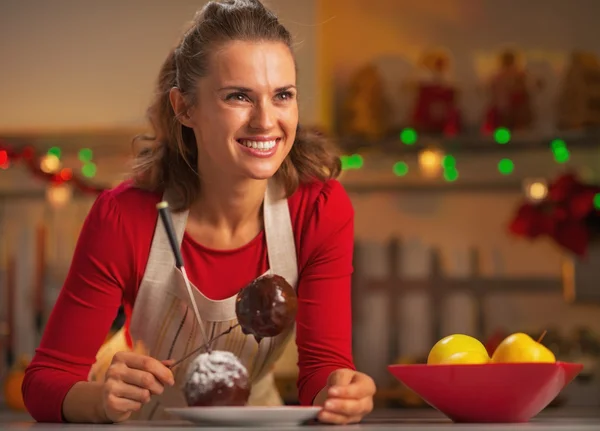 Porträt einer lächelnden jungen Hausfrau, die Apfel in Schokoglasur macht — Stockfoto