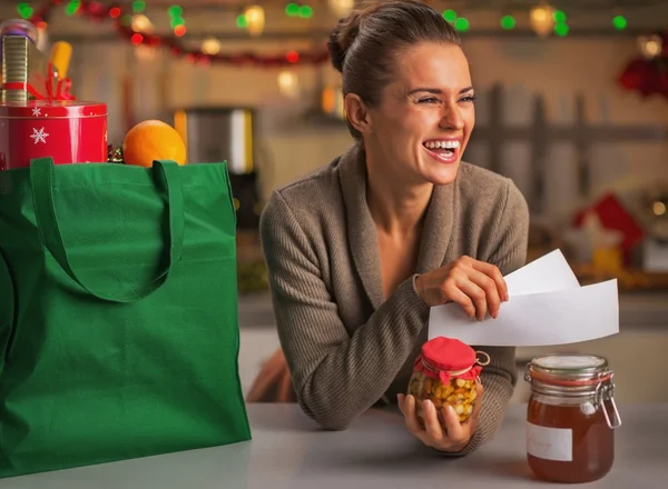 Leende ung hemmafru med kvitton från jul inköp — Stockfoto