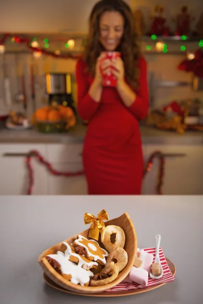 Weihnachtssnacks auf dem Tisch und junge Hausfrau im Hintergrund — Stockfoto