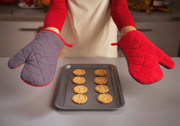 Kitchen gloves showing by young housewife and christmas cookies on pan