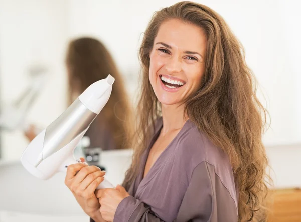 Sorrindo jovem segurando secador de cabelo — Fotografia de Stock