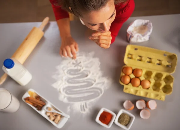 Gondolkodó fiatal háziasszony rajz karácsonyfát konyha lap — Stock Fotó