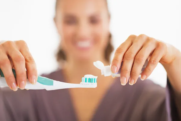 Close-up em feliz jovem mulher espremendo pasta de dentes de tubo — Fotografia de Stock