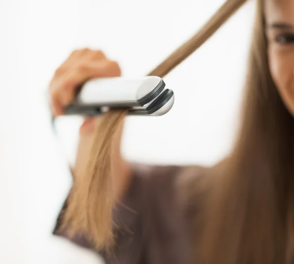 Primer plano de la mujer alisando el cabello con alisador — Foto de Stock