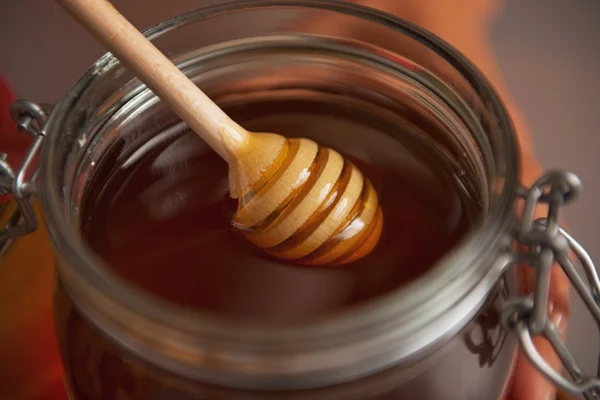 Closeup on honey dipper in honey jar — Stock Photo, Image