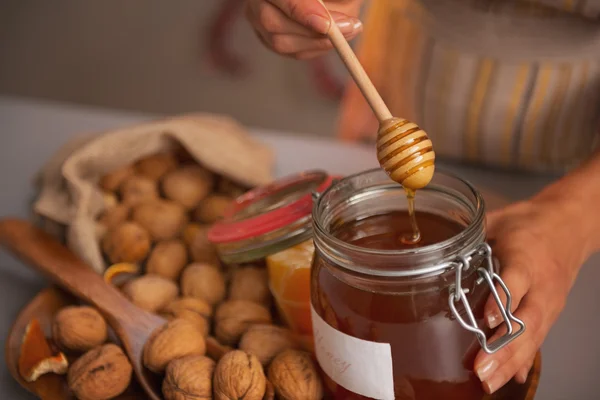 Closeup on young woman putting honey dipper in honey jar — Stock Photo, Image