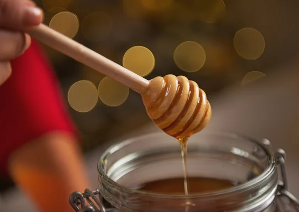 Closeup on honey flowing down from honey dipper in jar — Stock Photo, Image