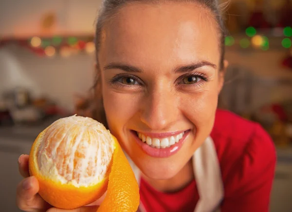 Portret van lachende jonge vrouw oranje in keuken tonen — Stockfoto