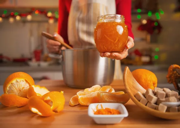 Jovem dona de casa fazendo geléia de laranja na cozinha decorada de Natal — Fotografia de Stock