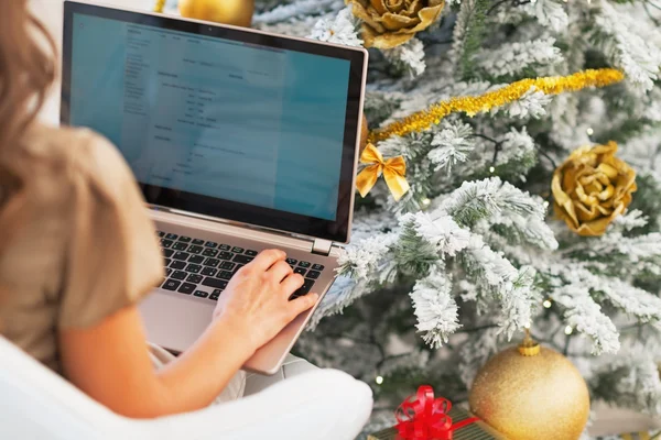 Close-up em mulher jovem usando laptop perto da árvore de Natal — Fotografia de Stock