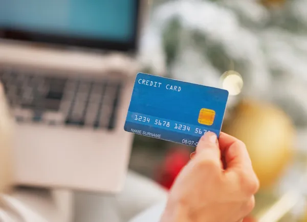 Primer plano en la tarjeta de crédito en la mano de la mujer con el ordenador portátil — Foto de Stock