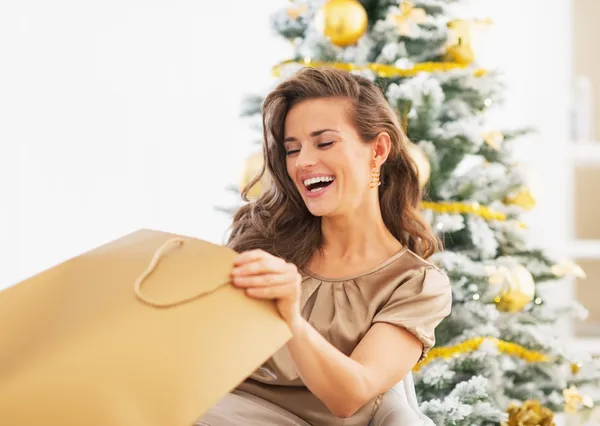 Mujer mirando en la bolsa de compras cerca del árbol de Navidad — Foto de Stock