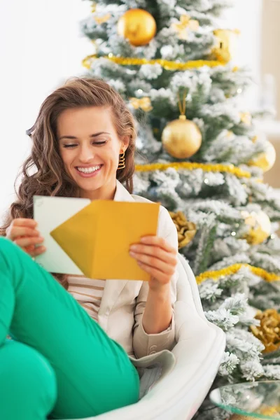 Mulher abrindo carta de Natal na frente da árvore de Natal — Fotografia de Stock