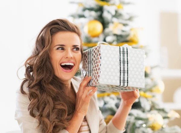 Mujer joven con caja de regalo de Navidad delante del árbol de Navidad —  Fotos de Stock