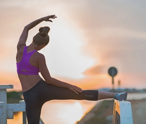 Healthy young woman stretching outdoors in the evening . rear vi — Stock Photo, Image