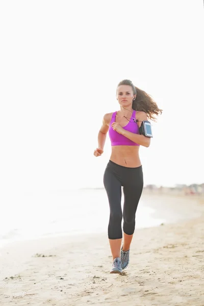 Fitness junge Frau läuft am Strand — Stockfoto