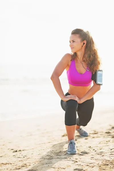 Full length portrait of fitness young woman stretching on beach — Stock Photo, Image