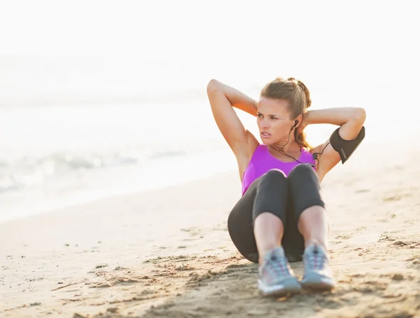 Fitness young woman doing abdominal crunch on beach — Stock Photo, Image