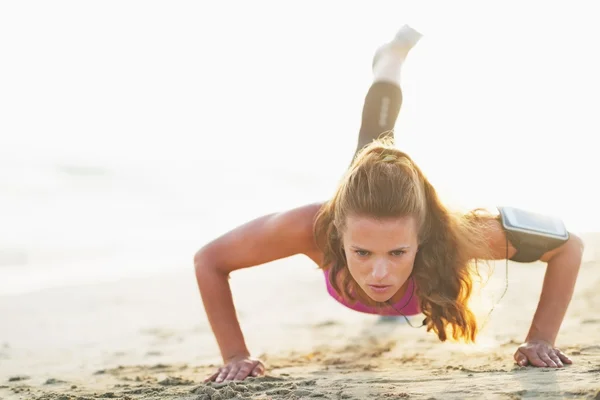 Kvinnliga idrottare gör push ups på stranden — Stockfoto