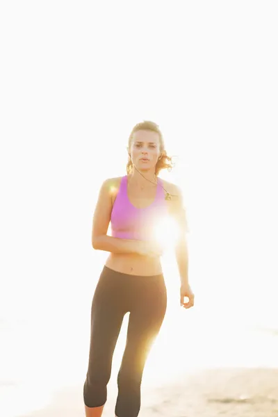 Fitness young woman running on beach — Stock Photo, Image