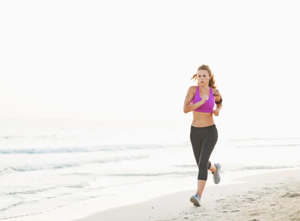 Healthy young woman running on beach — Stock Photo, Image