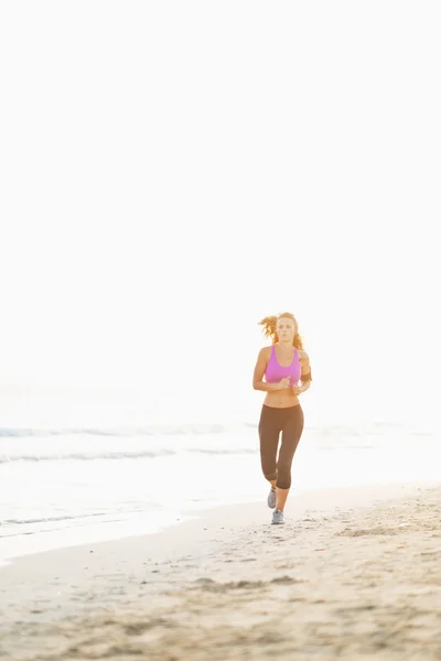 Fitness young woman running on beach — Stock Photo, Image