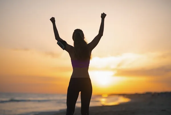 Silueta fitness mladá žena radost na pláži za soumraku — Stock fotografie