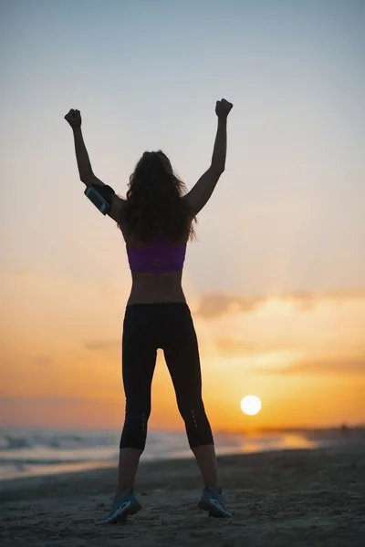 Silhouette of fitness young woman rejoicing on beach at dusk — Stock Photo, Image