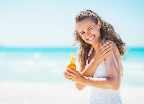 Leende ung kvinna tillämpa solskyddskräm crème på stranden — Stockfoto