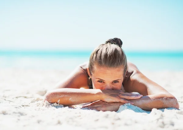 Young woman in swimsuit laying on sandy beach — Stock Photo, Image