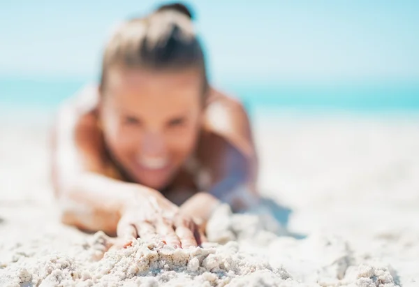 Closeup on happy young woman in swimsuit laying on sandy beach — Stock Photo, Image