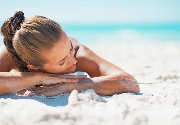 Happy young woman in swimsuit relaxing while laying on sandy bea — Stock Photo, Image