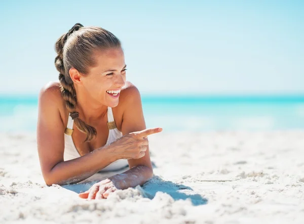 Smiling young woman in swimsuit laying on beach — Stock Photo, Image