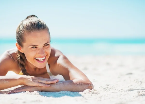 Smiling young woman in swimsuit enjoying laying on beach — Stock Photo, Image